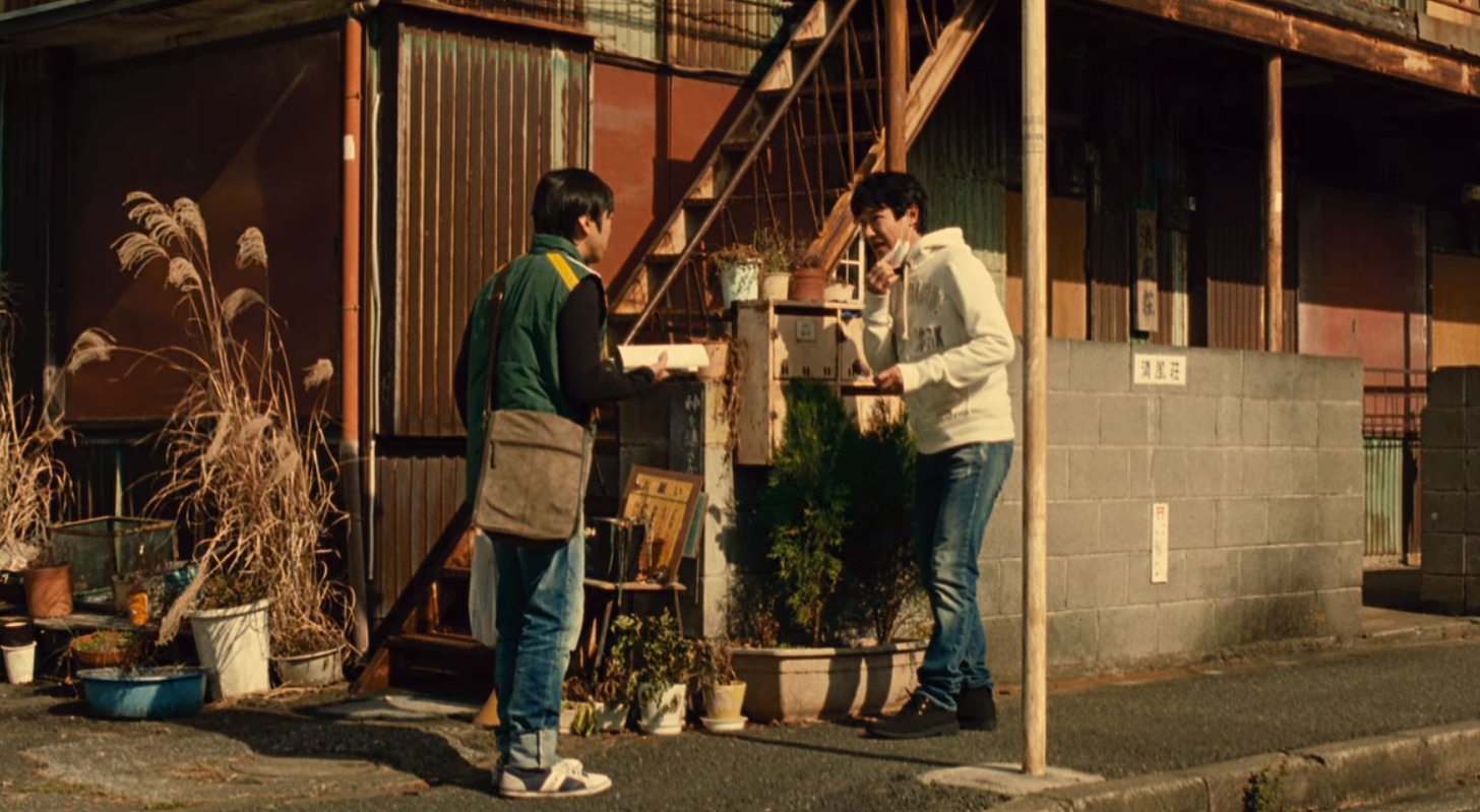 映画「鍵泥棒のメソッド」にて主人公桜井が住むアパートの前で会話する桜井とコンドウの二人